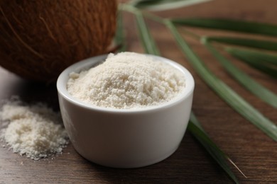 Photo of Organic coconut flour in bowl on wooden table, closeup