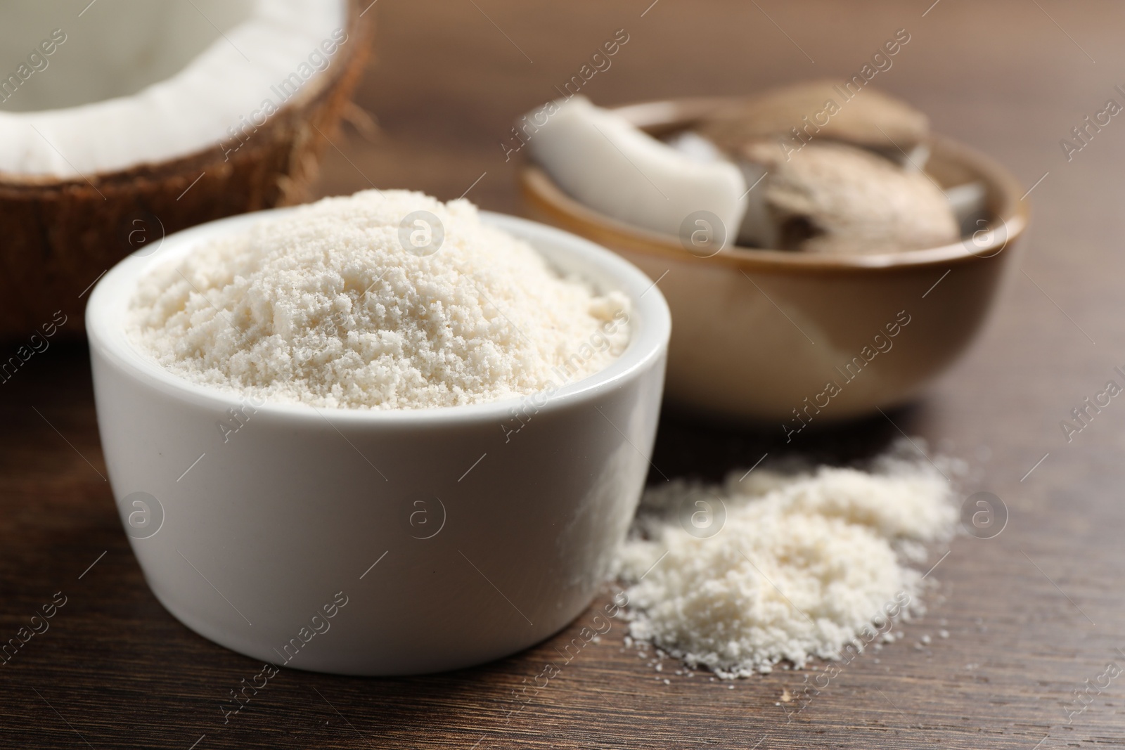 Photo of Organic coconut flour in bowl on wooden table, closeup