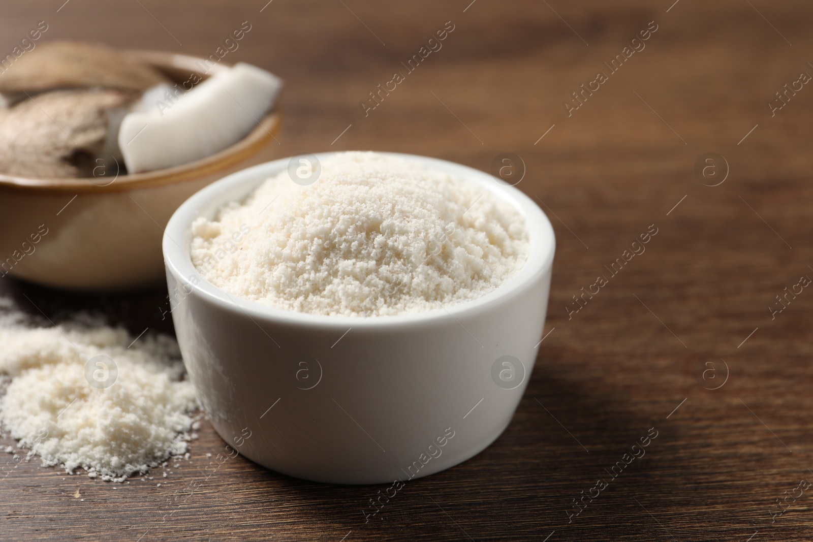 Photo of Organic coconut flour in bowl on wooden table, closeup