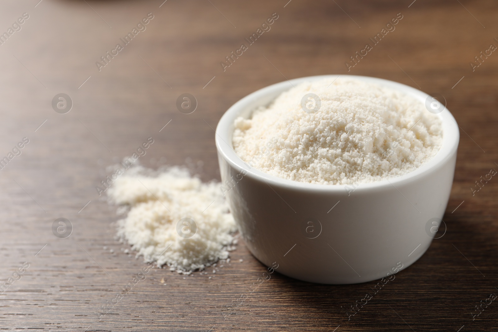 Photo of Organic coconut flour in bowl on wooden table, closeup