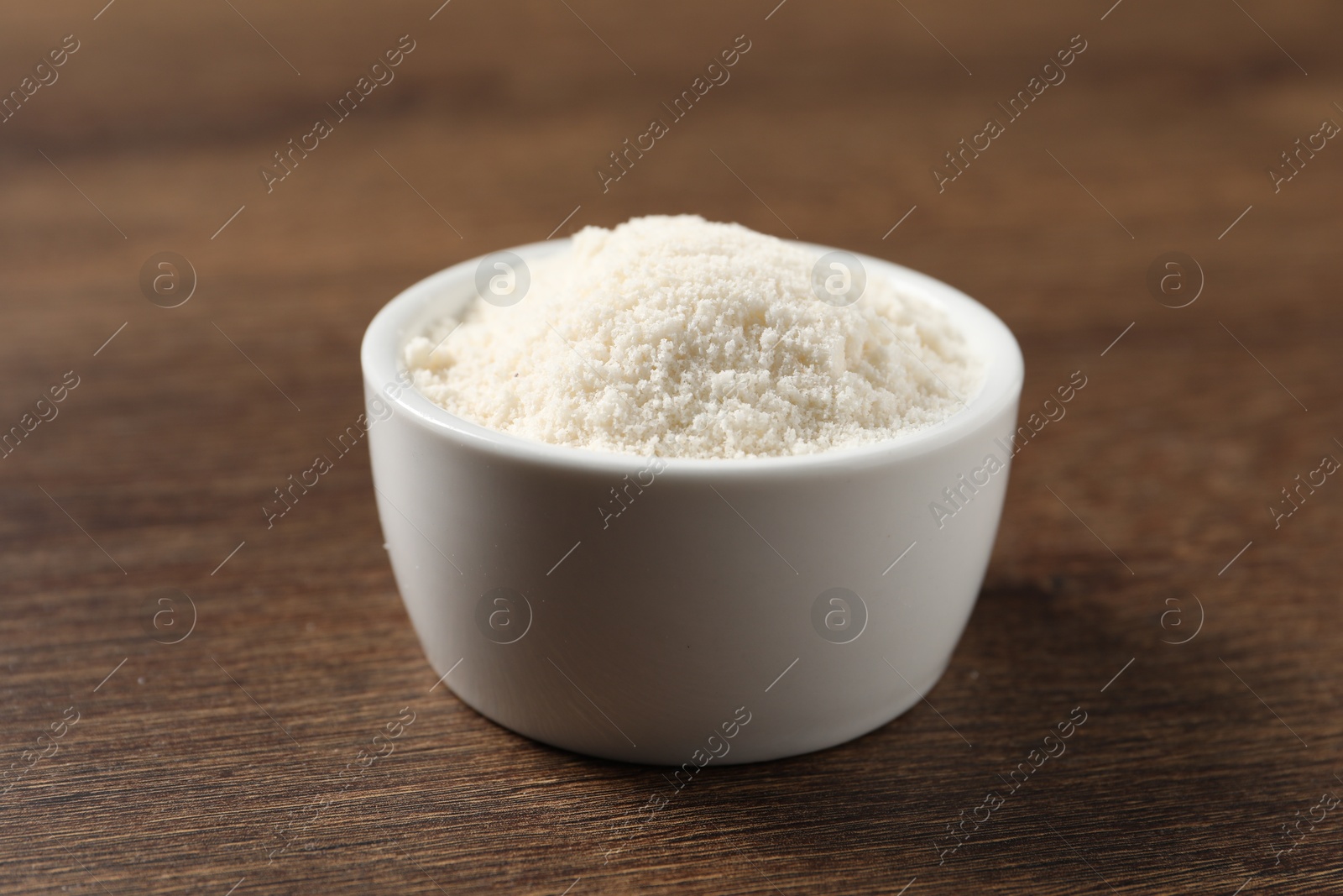 Photo of Organic coconut flour in bowl on wooden table, closeup