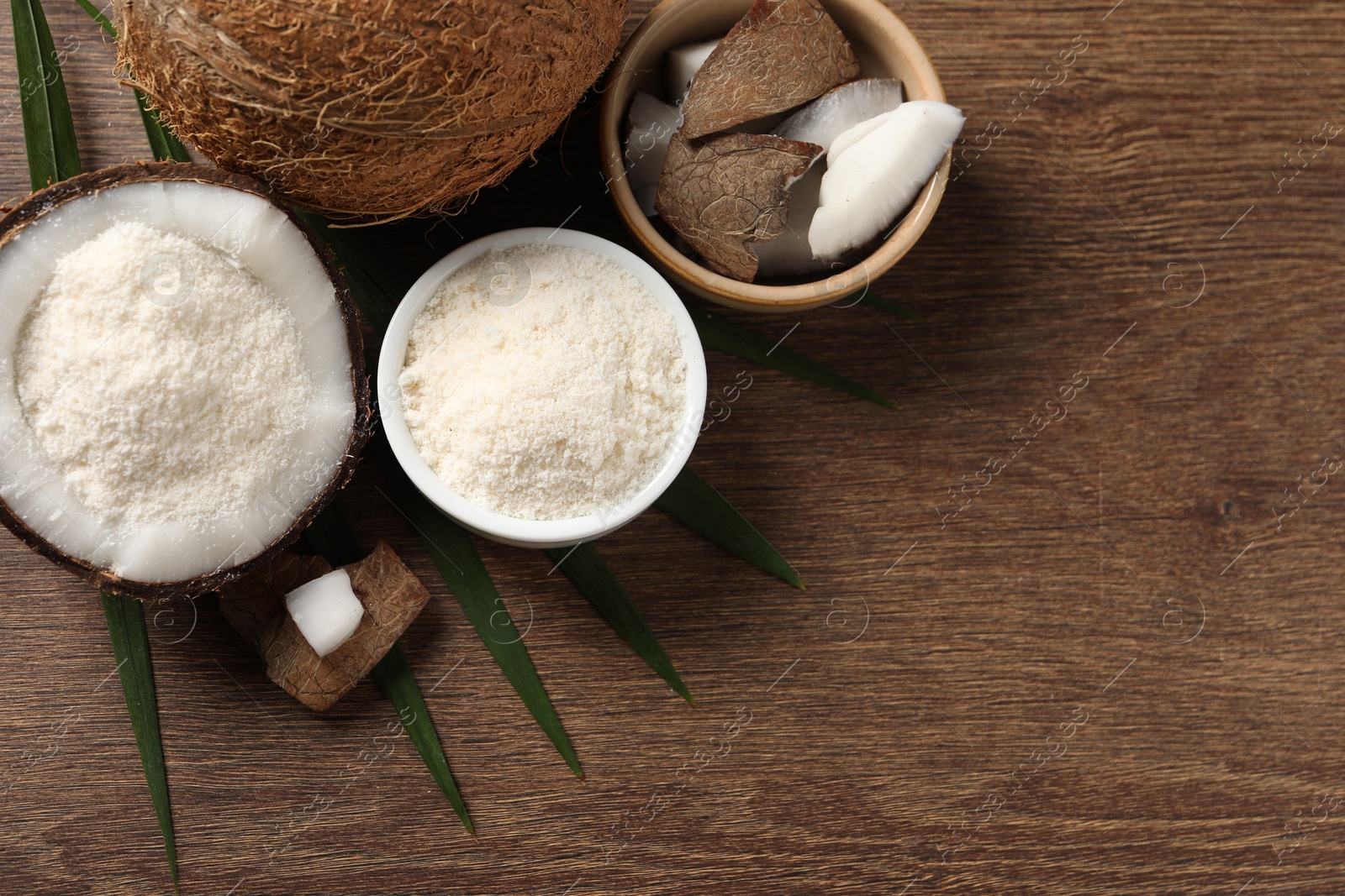 Photo of Coconut flour and fresh fruits on wooden table, flat lay. Space for text