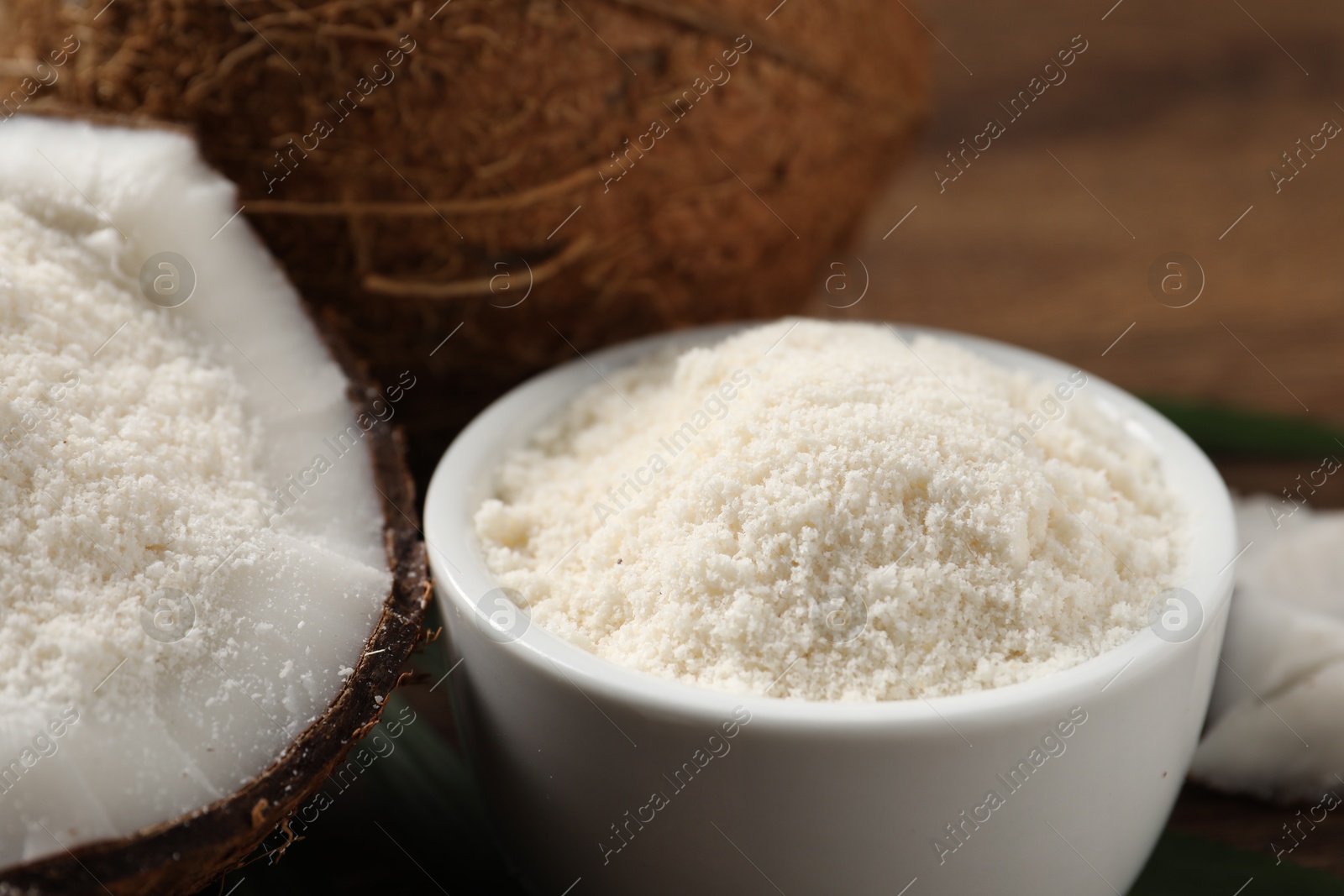 Photo of Coconut flour in bowl and fresh fruits on table, closeup