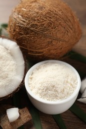 Photo of Coconut flour in bowl and fresh fruits on wooden table, closeup