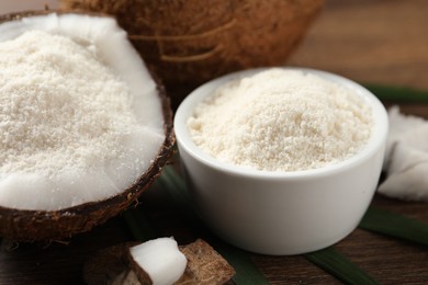 Photo of Coconut flour in bowl and fresh fruits on wooden table, closeup