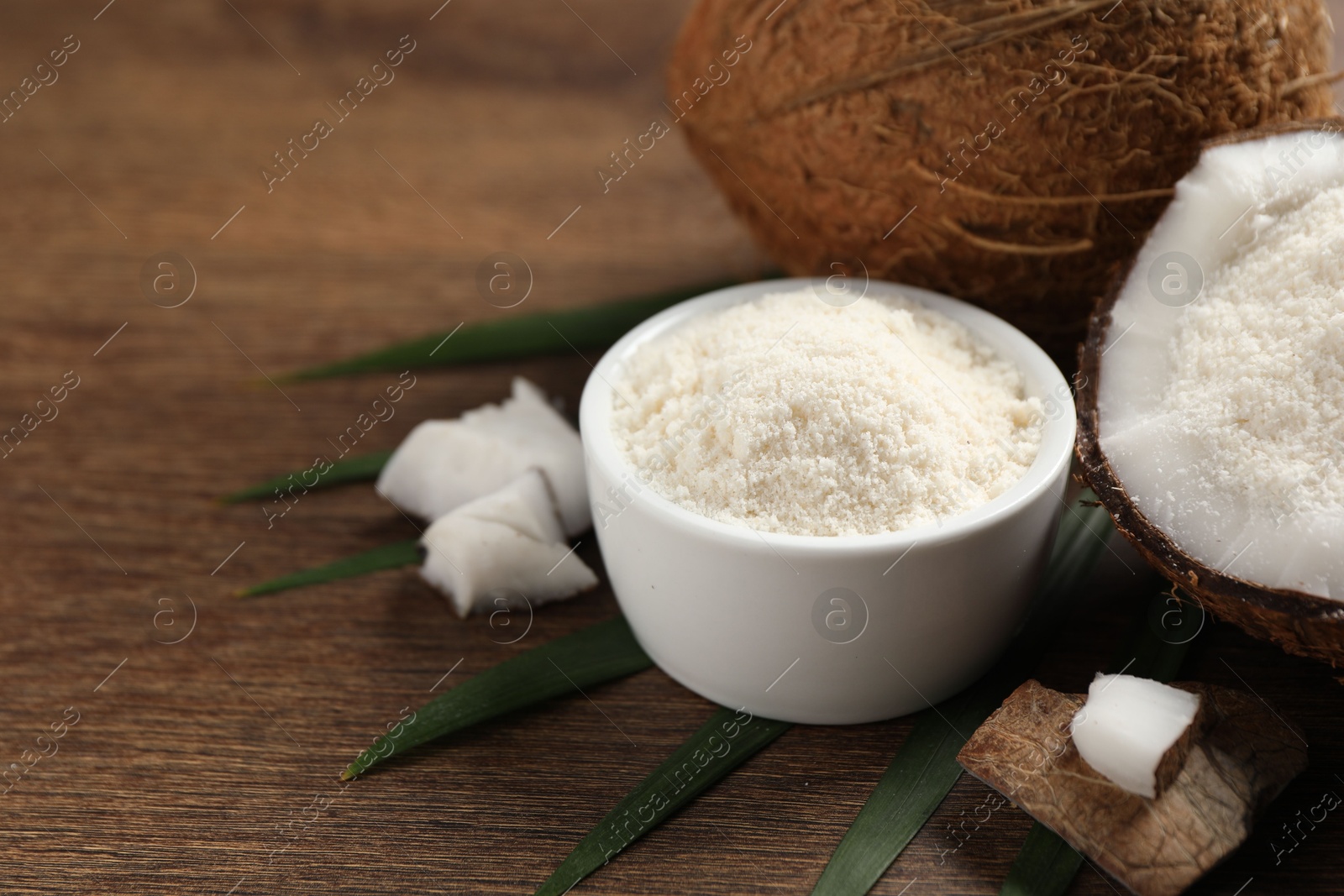 Photo of Coconut flour and fresh fruits on wooden table, closeup. Space for text