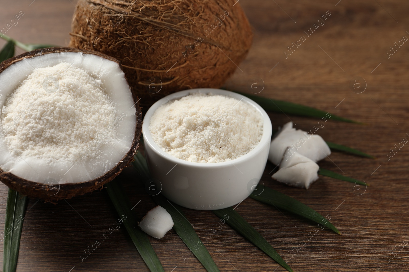 Photo of Coconut flour and fresh fruits on wooden table, closeup