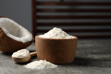 Photo of Organic coconut flour in bowl, spoon and fresh fruits on grey table