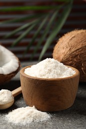 Photo of Organic coconut flour in bowl, spoon and fresh fruits on grey table