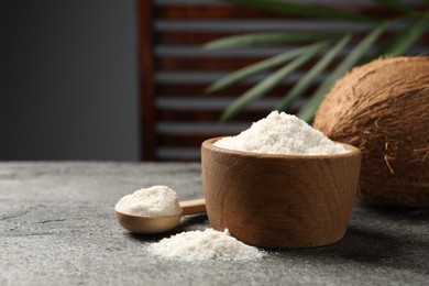 Photo of Organic coconut flour in bowl, spoon and fresh fruits on grey table. Space for text