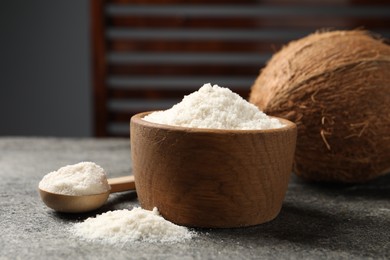 Photo of Coconut flour in bowl, spoon and fresh fruit on grey table, closeup