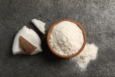 Photo of Organic coconut flour in bowl and fruit pieces on grey table, flat lay