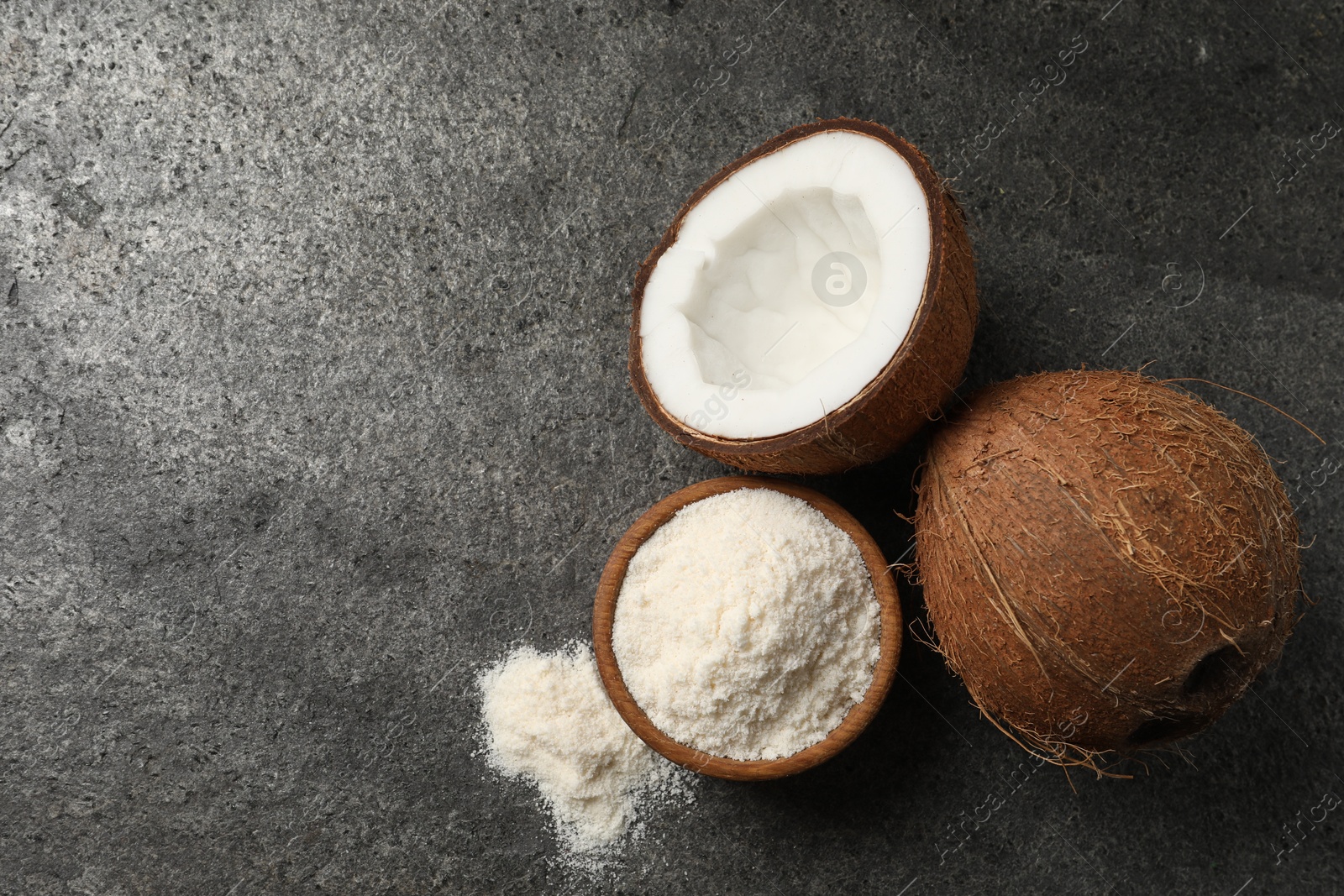 Photo of Organic coconut flour in bowl and fresh fruits on grey table, flat lay. Space for text