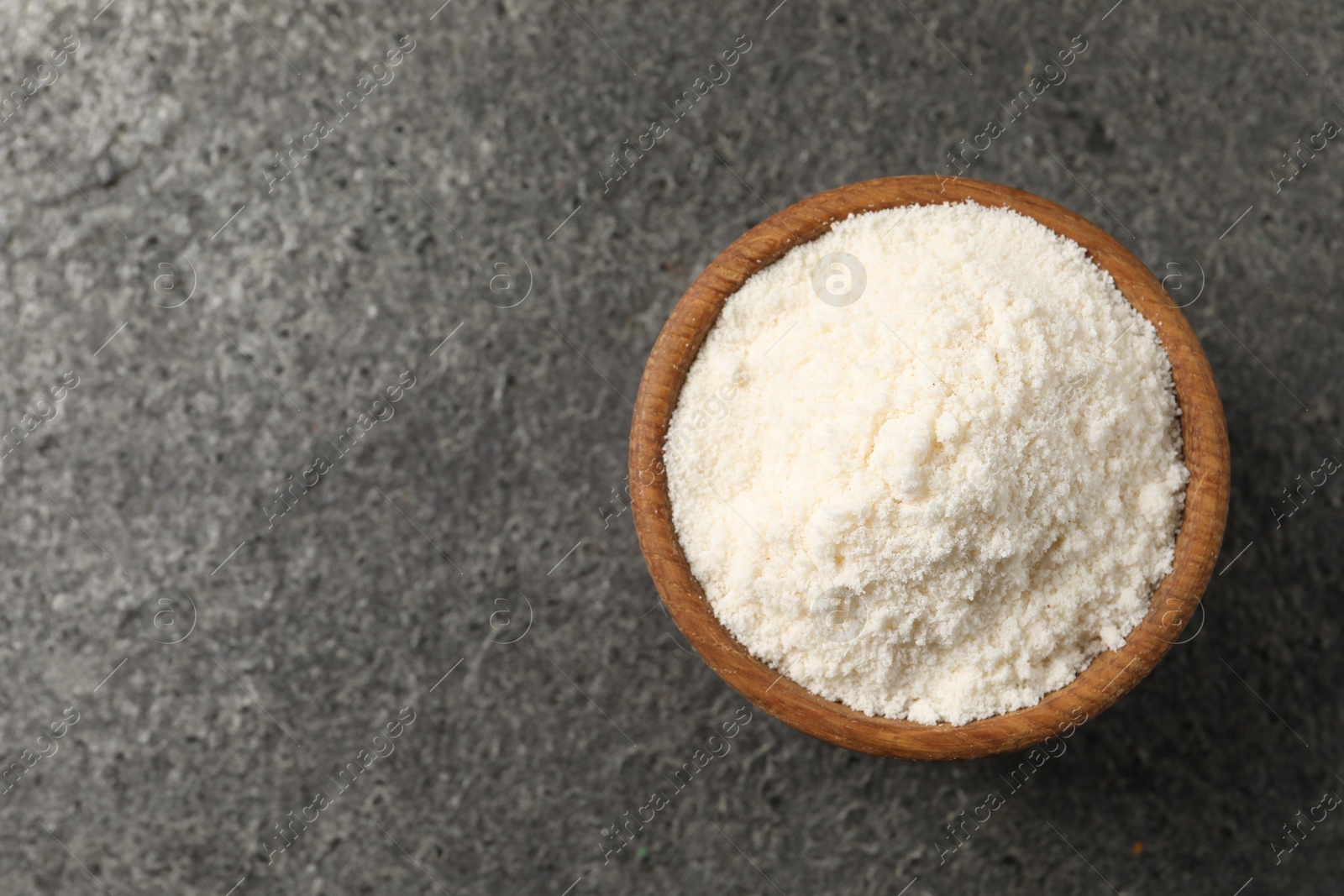 Photo of Organic coconut flour in bowl on grey table, top view. Space for text