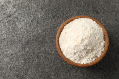 Photo of Organic coconut flour in bowl on grey table, top view. Space for text