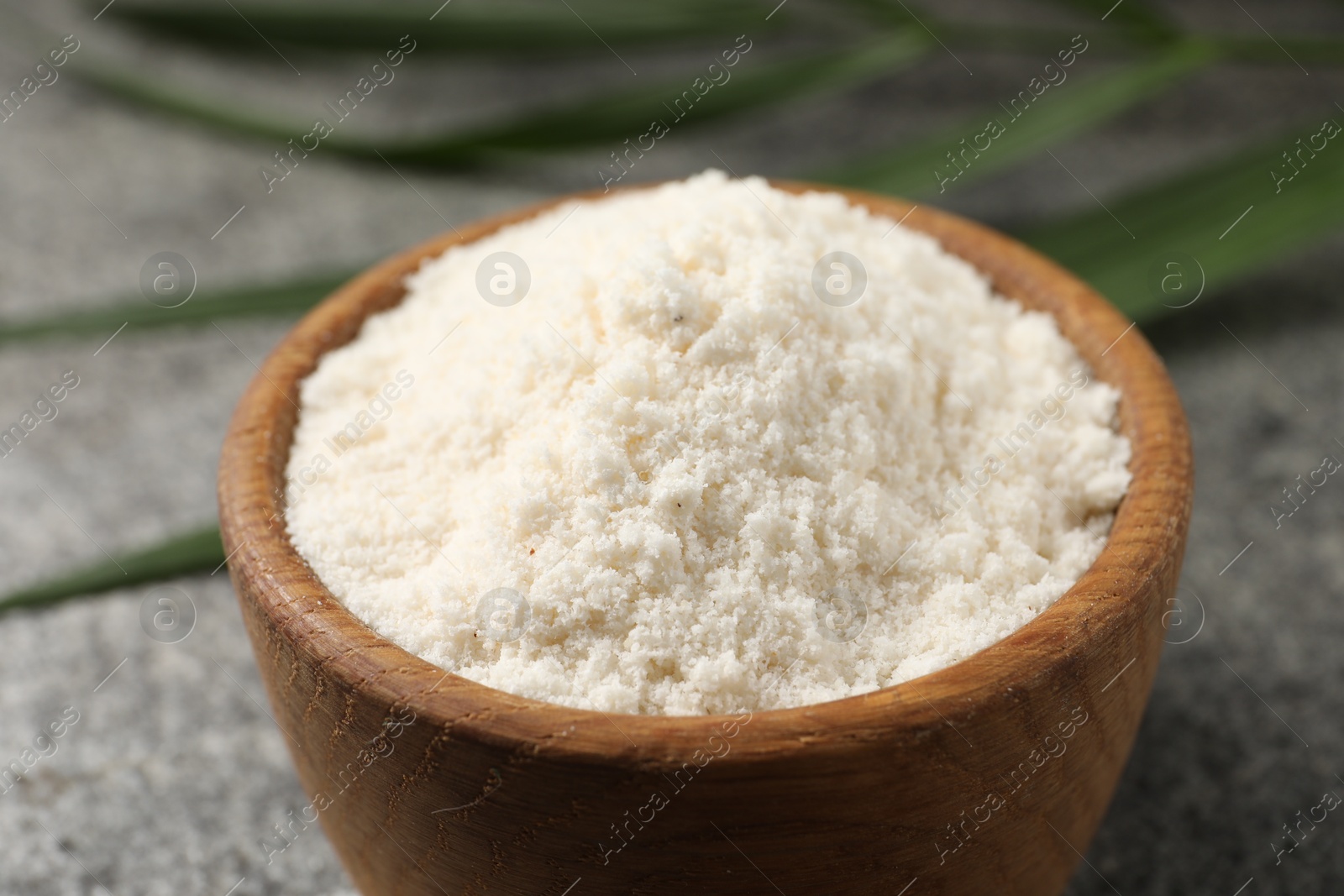 Photo of Organic coconut flour in bowl on grey table, closeup