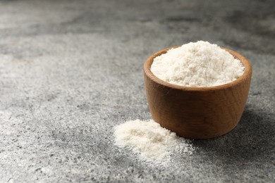 Photo of Organic coconut flour in bowl on grey table. Space for text