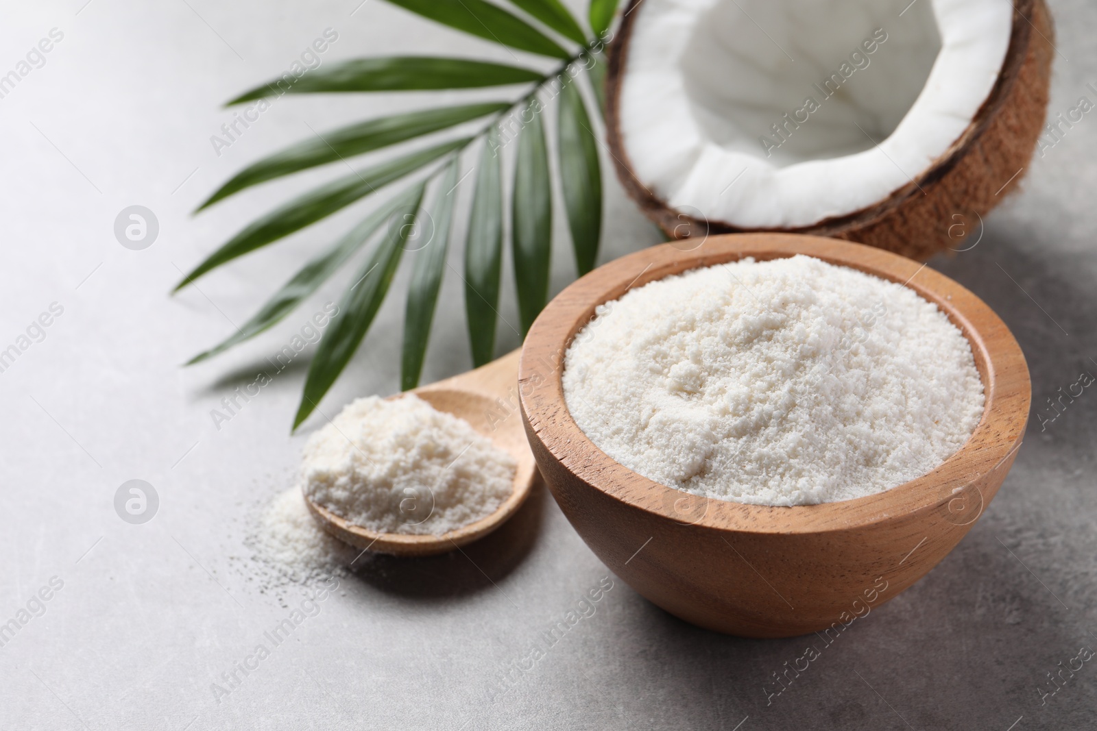 Photo of Organic coconut flour, fresh fruit and leaf on light grey table, closeup