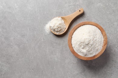 Photo of Organic coconut flour in bowl and spoon on light grey table, flat lay. Space for text