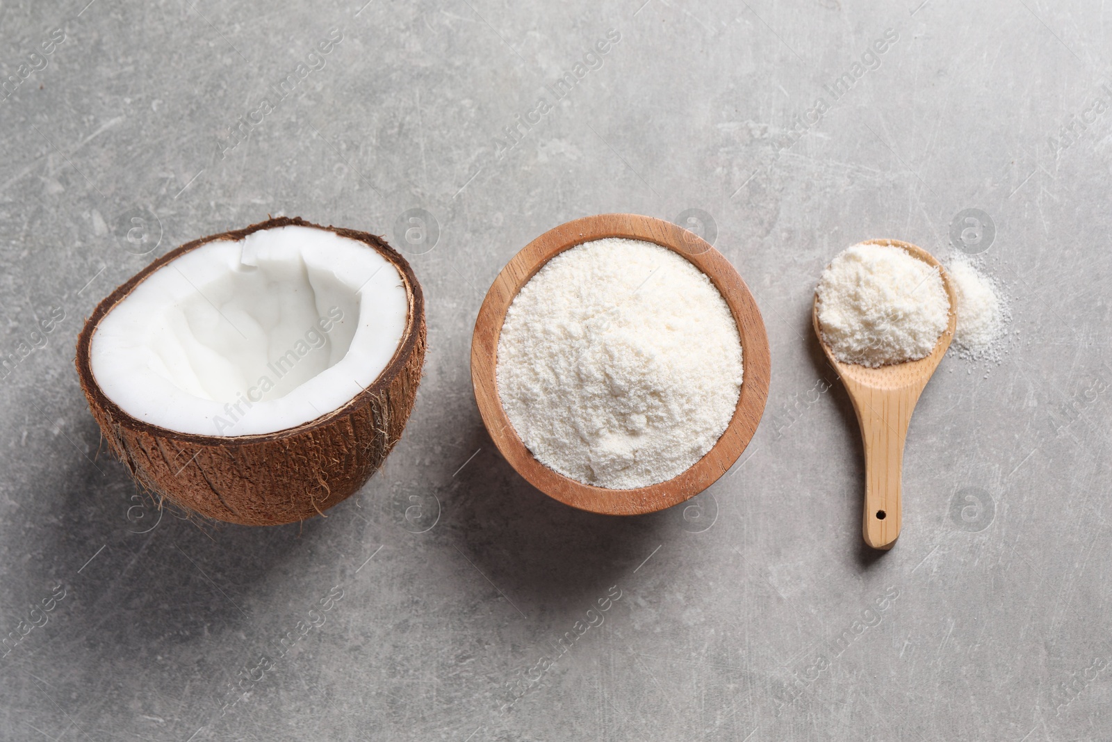 Photo of Organic coconut flour in bowl, spoon and fresh fruit on light grey table, flat lay