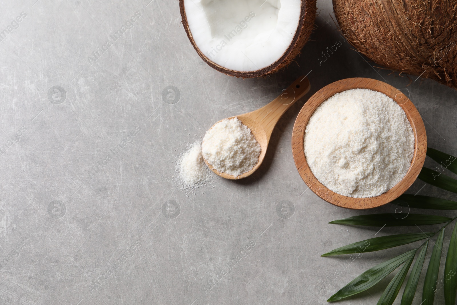 Photo of Organic coconut flour, fresh fruits and leaf on light grey table, flat lay. Space for text