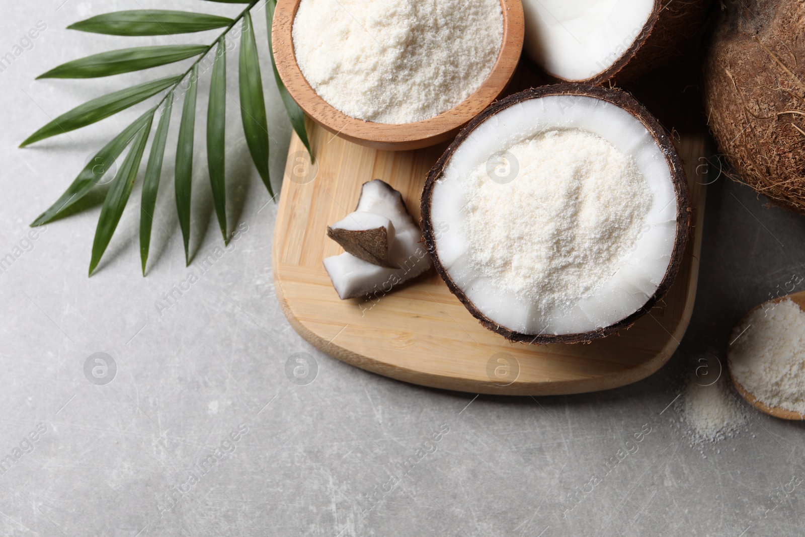 Photo of Organic coconut flour, fresh fruits and leaf on light grey table, flat lay. Space for text