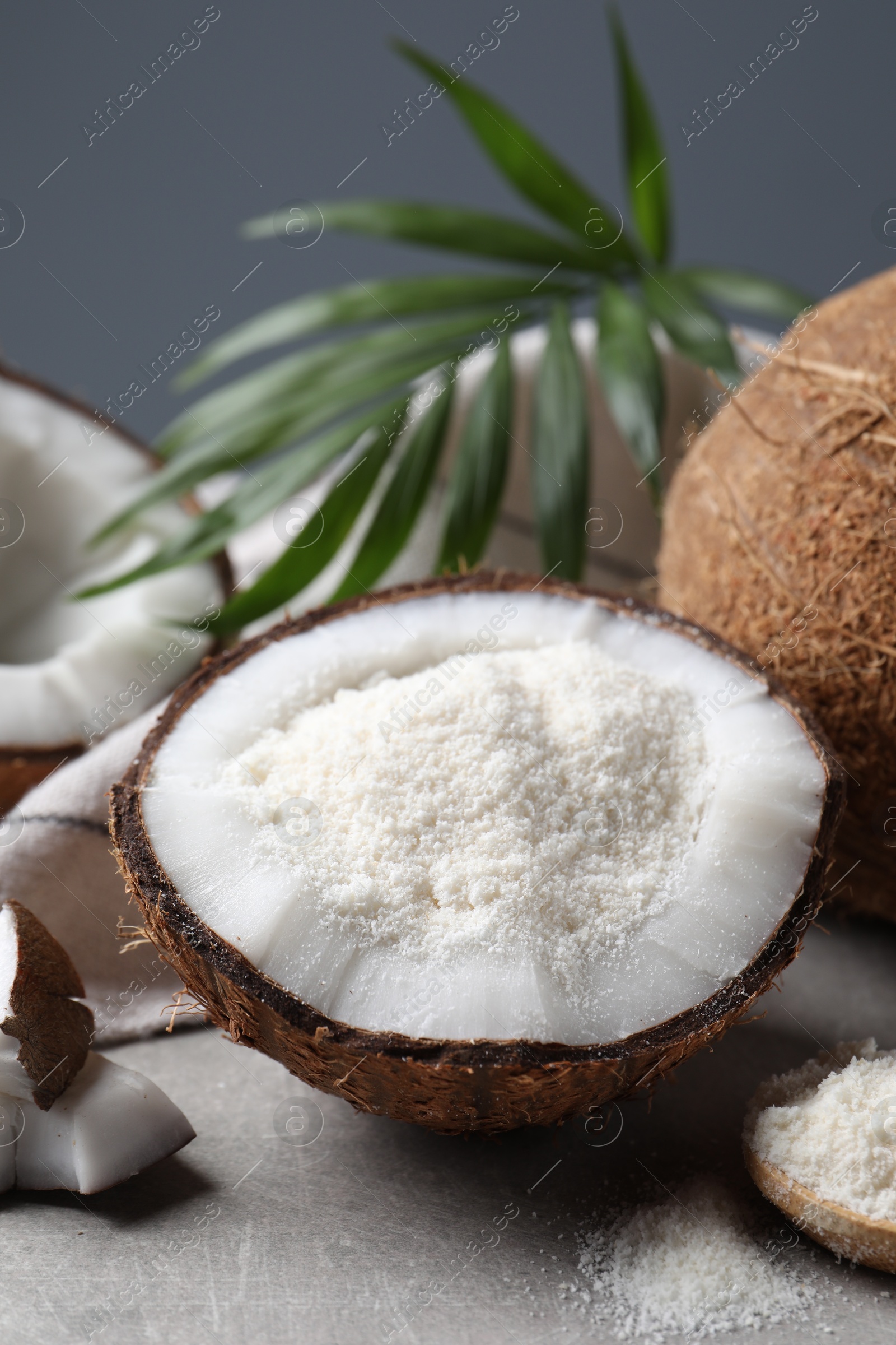 Photo of Organic coconut flour, fresh fruits and leaf on light grey table, closeup