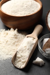 Photo of Coconut flour and fruit pieces on dark grey table, closeup