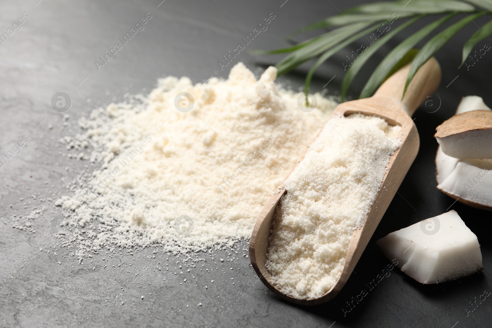 Photo of Coconut flour and fruit pieces on dark grey table, closeup