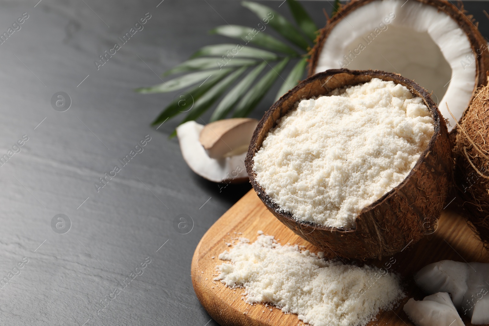 Photo of Organic coconut flour and fresh fruits on black table, closeup. Space for text