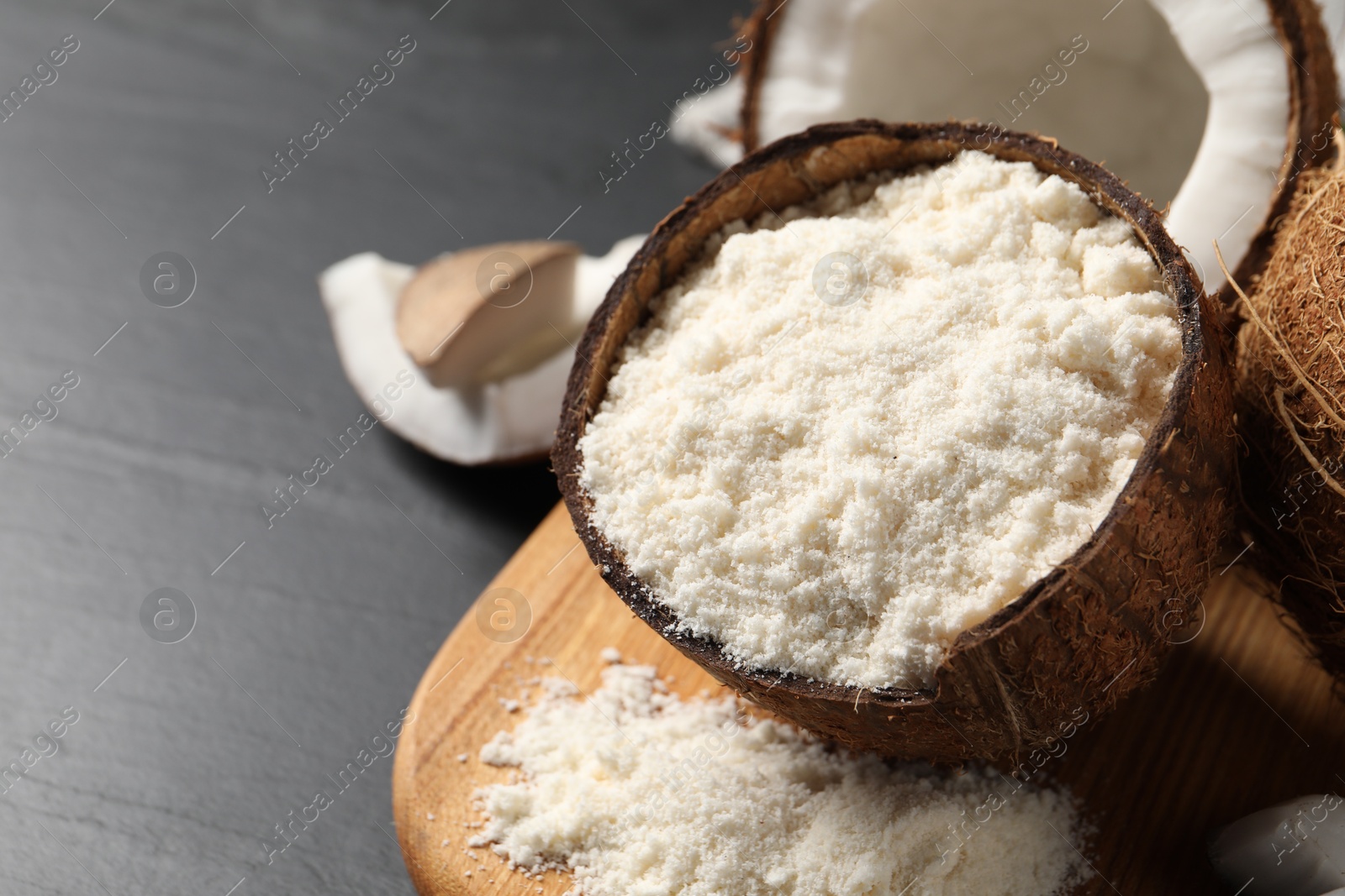 Photo of Organic coconut flour and fresh fruits on black table, closeup. Space for text