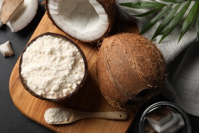 Photo of Organic coconut flour and fresh fruits on black table, flat lay