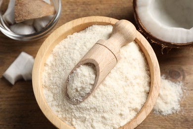 Photo of Coconut flour in bowl, scoop and fresh fruits on wooden table, flat lay