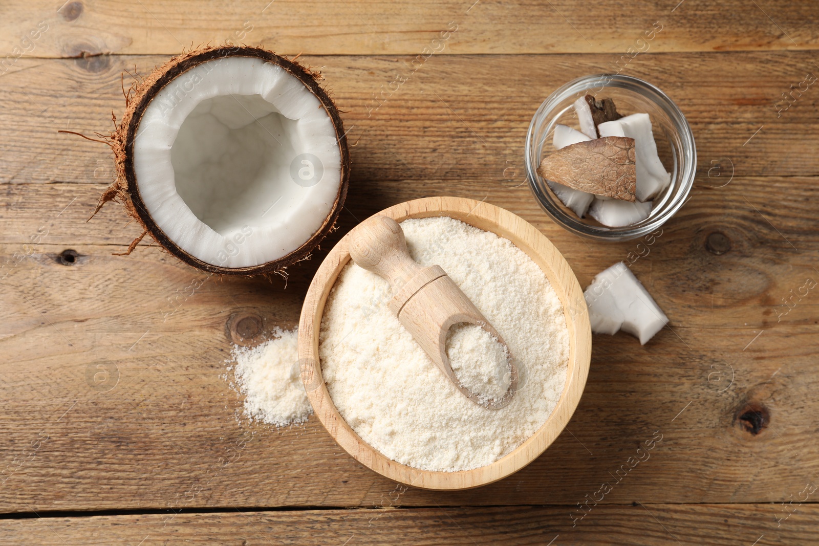 Photo of Coconut flour in bowl, scoop and fresh fruits on wooden table, flat lay