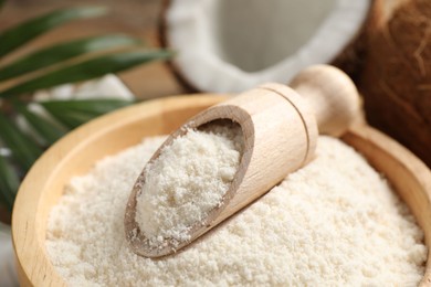 Photo of Coconut flour in bowl and scoop on table, closeup