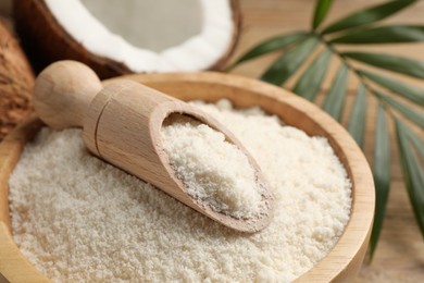 Photo of Coconut flour in bowl and scoop on table, closeup