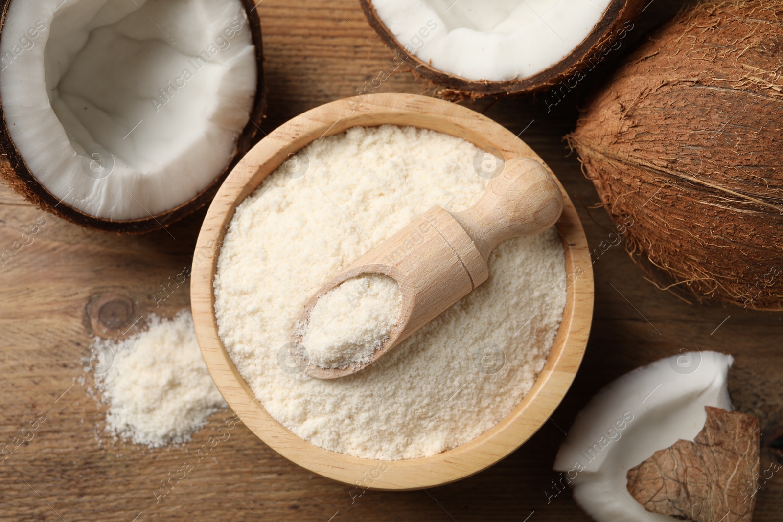 Photo of Coconut flour in bowl, scoop and fresh fruits on wooden table, flat lay