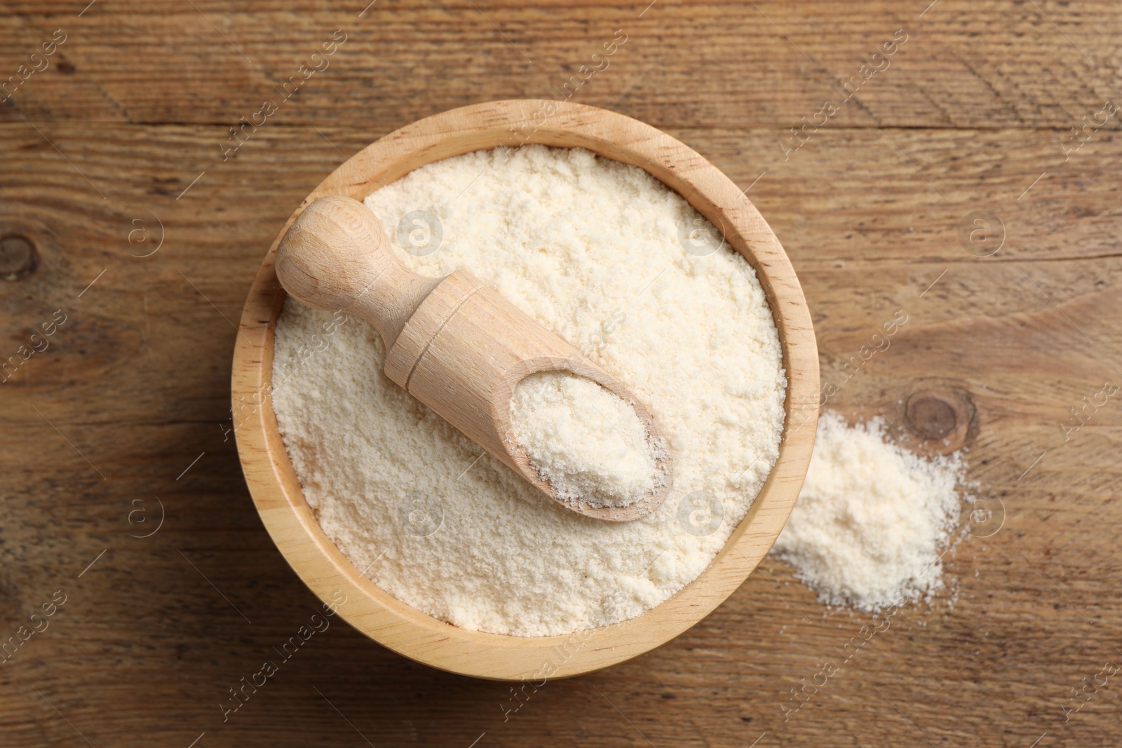 Photo of Organic coconut flour in bowl and scoop on wooden table, top view