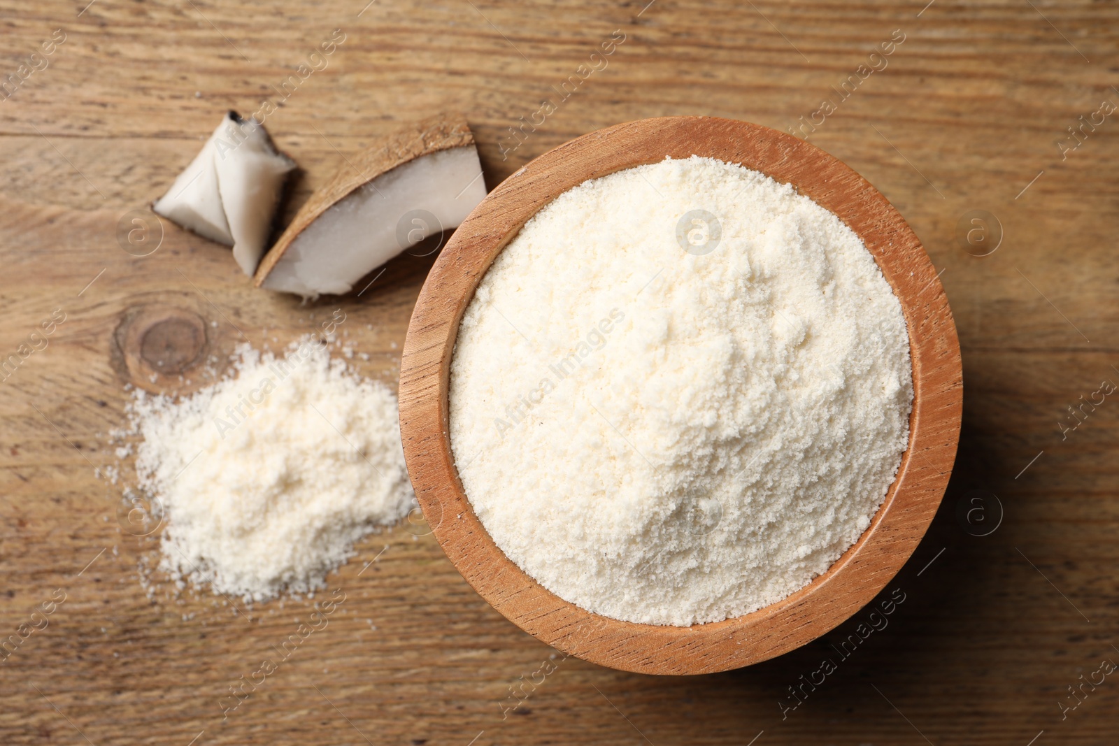 Photo of Organic coconut flour in bowl on wooden table, flat lay