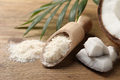 Photo of Coconut flour in scoop, fresh fruits and leaf on wooden table, closeup