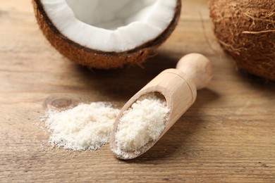 Photo of Coconut flour in scoop and fresh fruits on wooden table, closeup