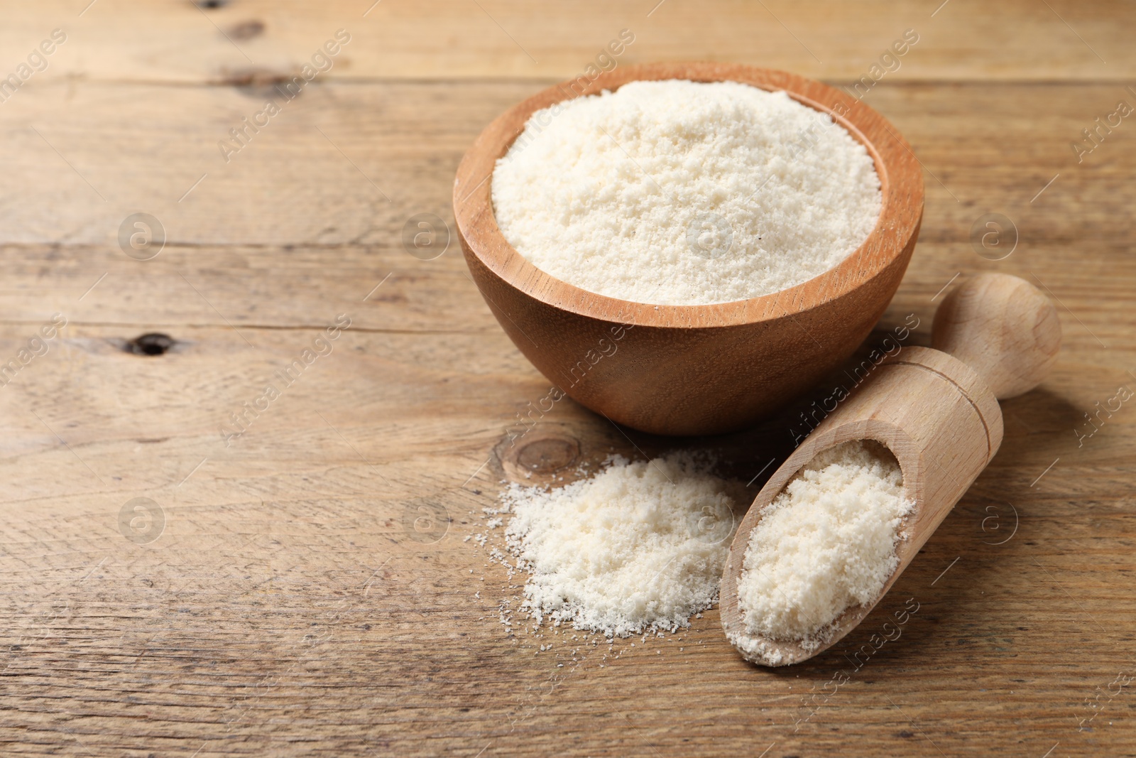 Photo of Coconut flour in bowl and scoop on wooden table. Space for text