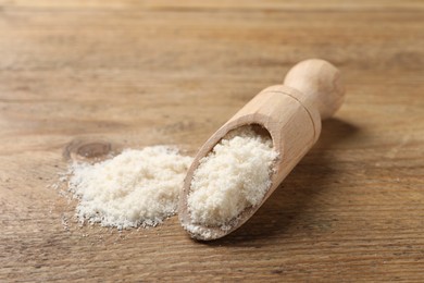 Photo of Scoop with organic coconut flour on wooden table, closeup