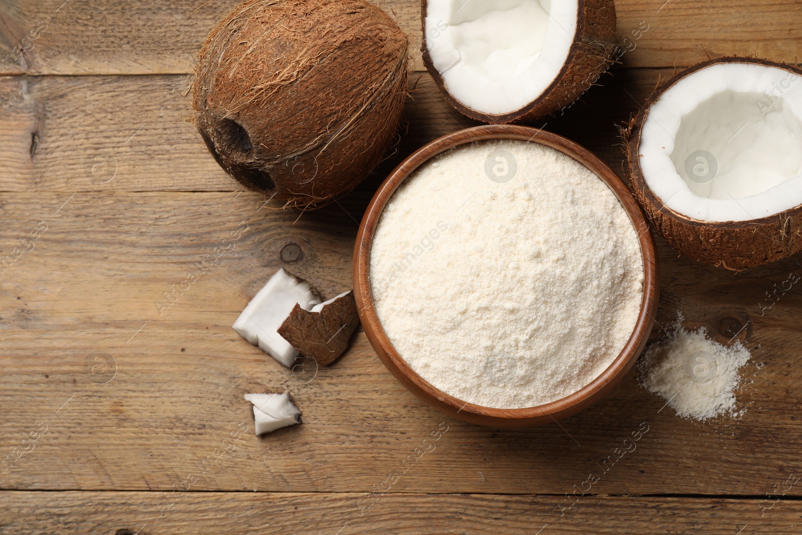 Photo of Organic coconut flour in bowl and fresh fruits on wooden table, flat lay