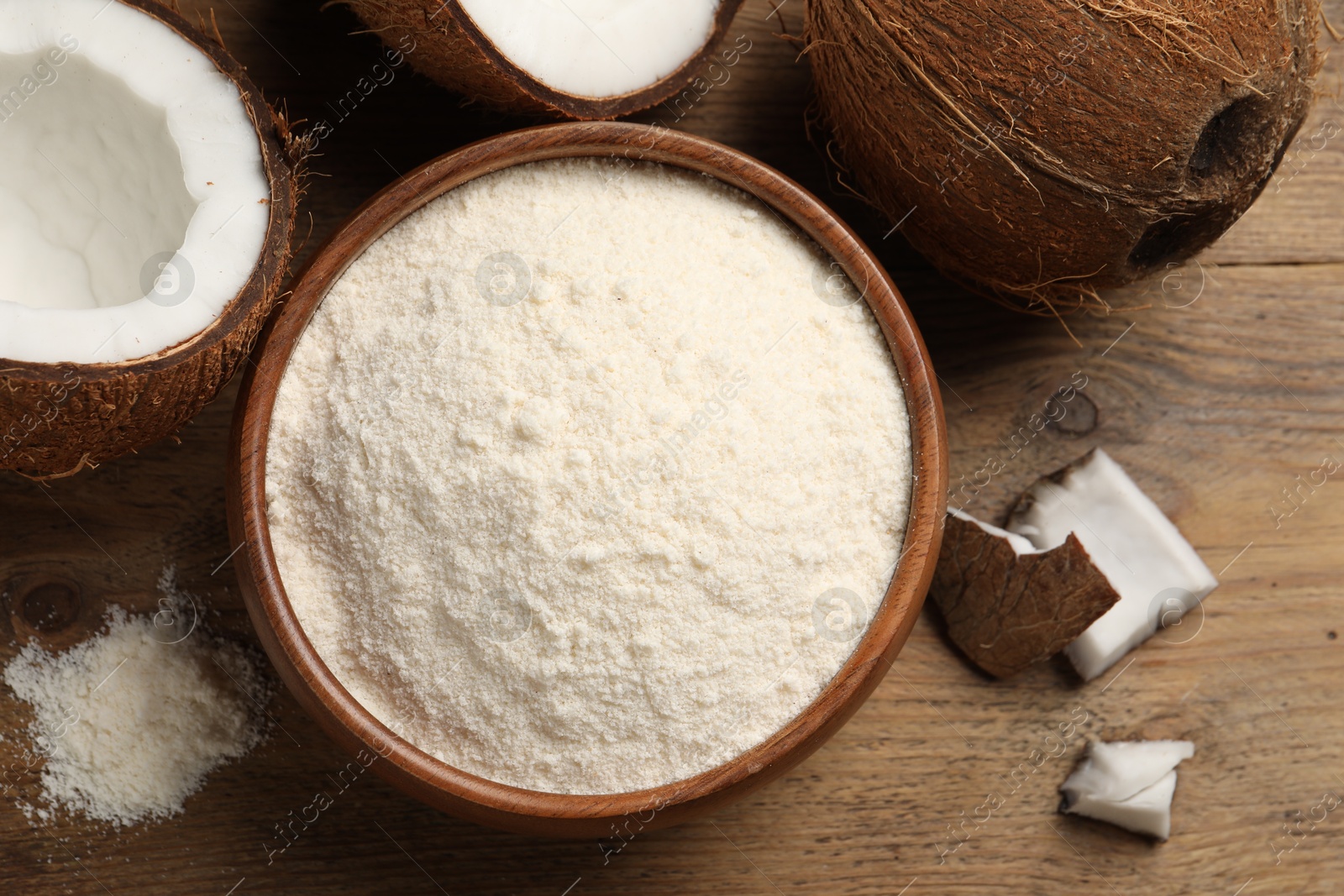 Photo of Organic coconut flour in bowl and fresh fruits on wooden table, flat lay