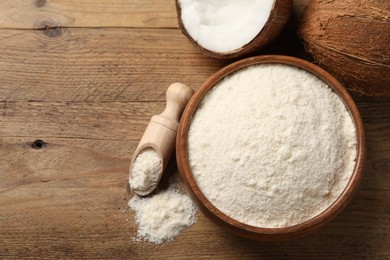 Photo of Coconut flour in bowl, scoop and fresh fruits on wooden table, flat lay. Space for text