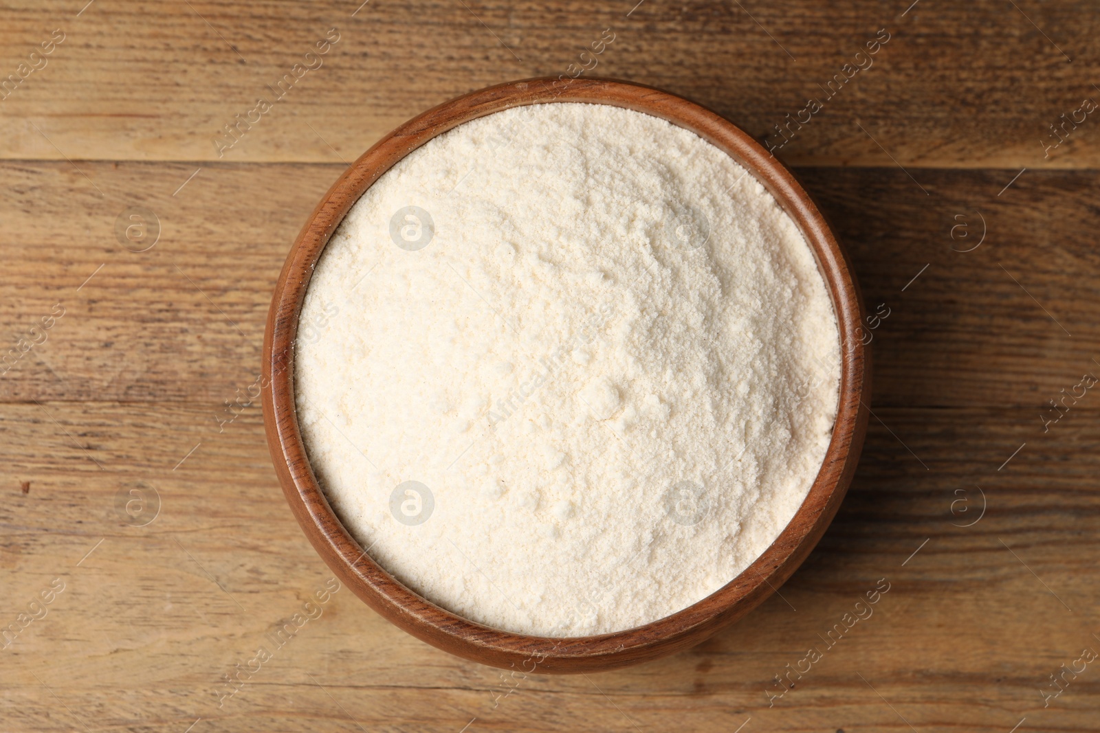 Photo of Coconut flour in bowl on wooden table, top view