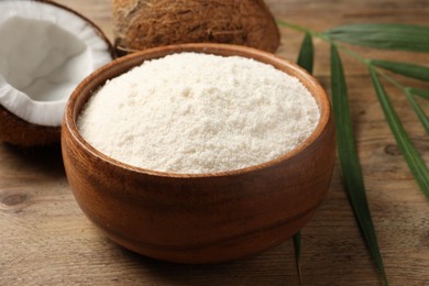 Photo of Coconut flour in bowl and fresh fruits on table, closeup