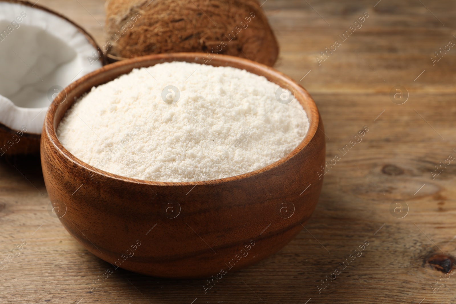 Photo of Coconut flour in bowl and fresh fruits on table, closeup