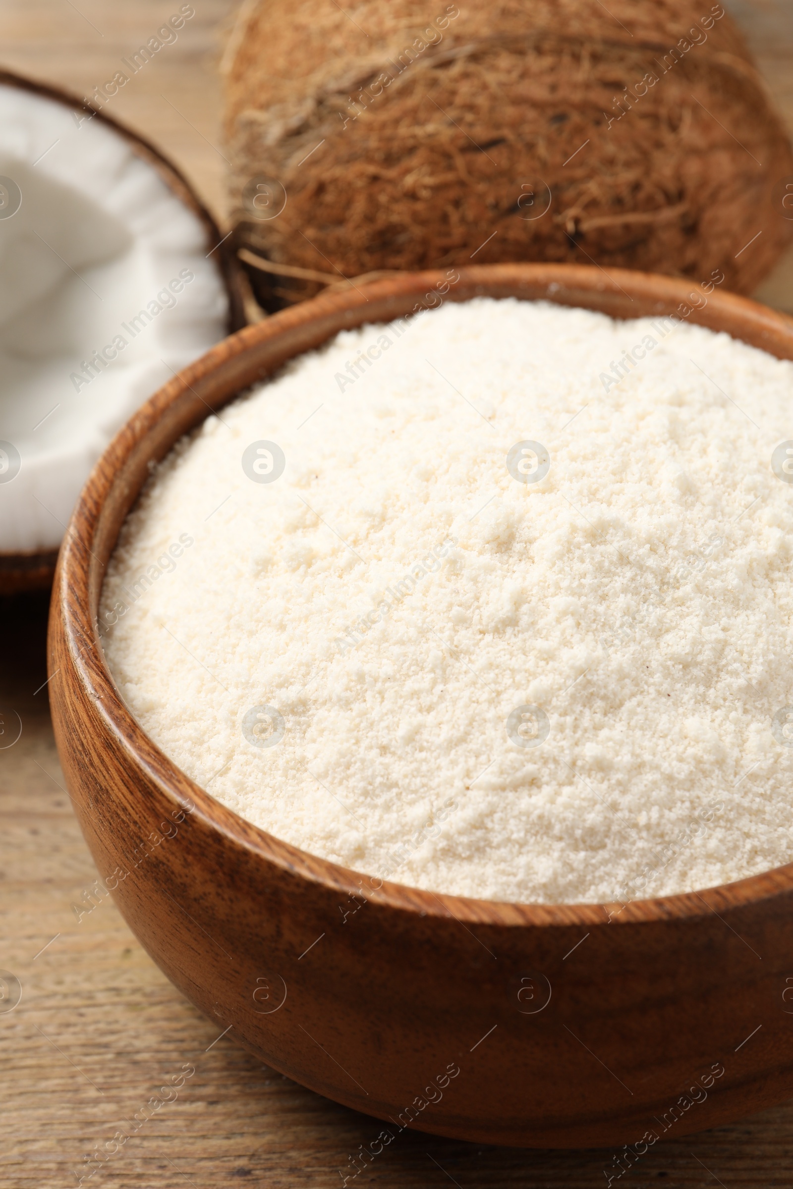 Photo of Coconut flour in bowl and fresh fruits on table, closeup